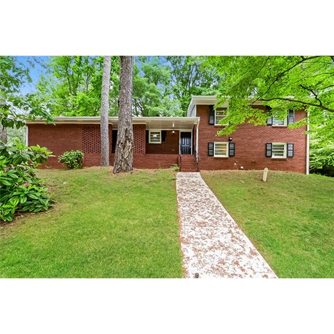 a brick house with a lawn and trees