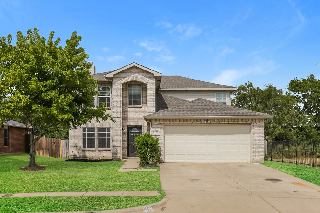 A house with a garage and a tree in front.