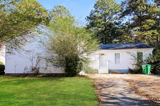 a white house with a driveway and a tree in front of it