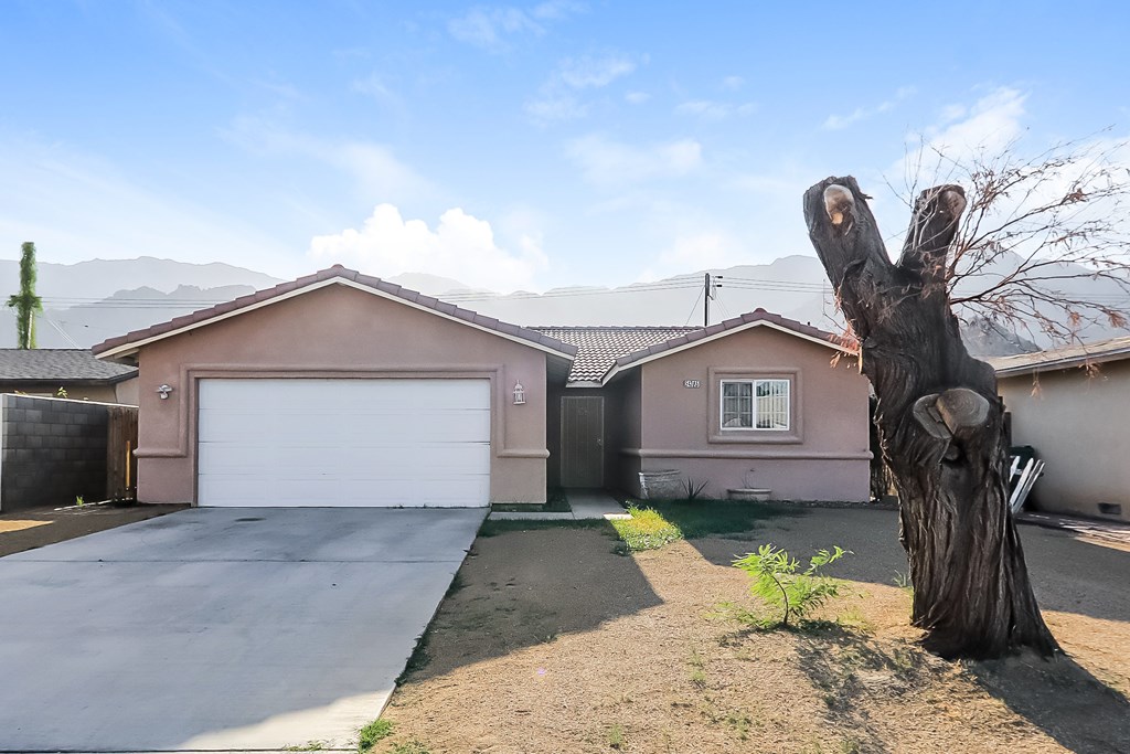A tree stump stands in the front yard of a house with a garage.