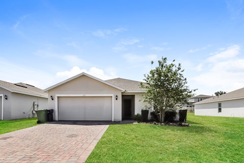 A house with a garage and a tree in front.