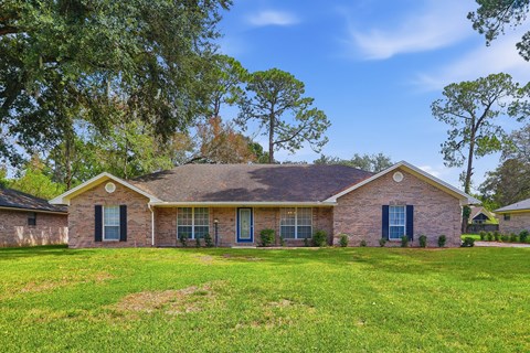 A house with a green lawn and trees in the background.