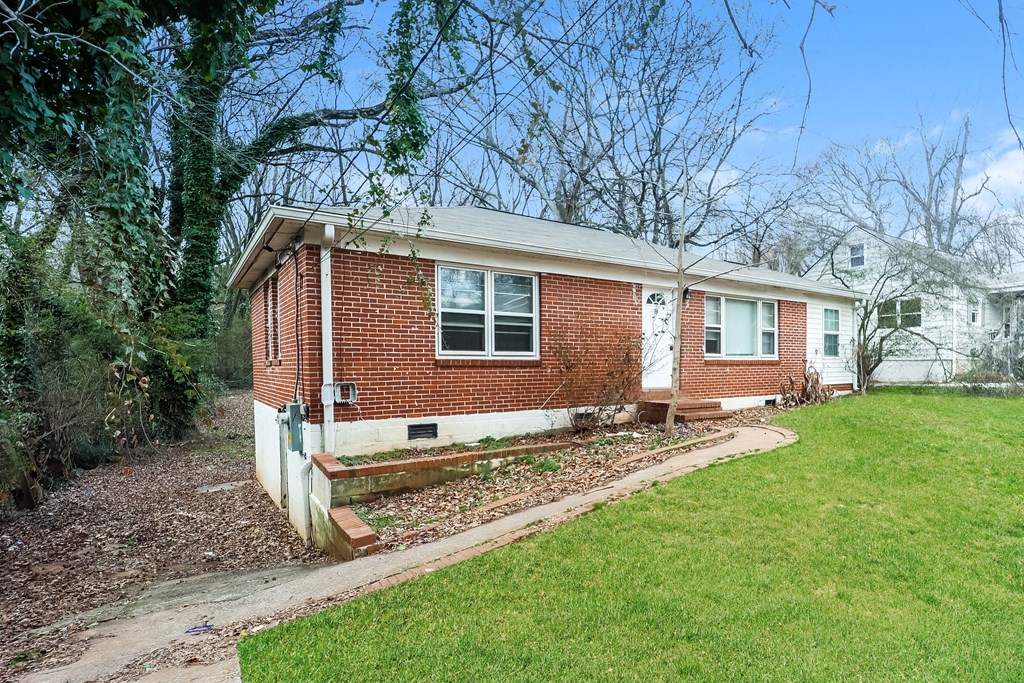 A red brick house with a white window and a green lawn in front.