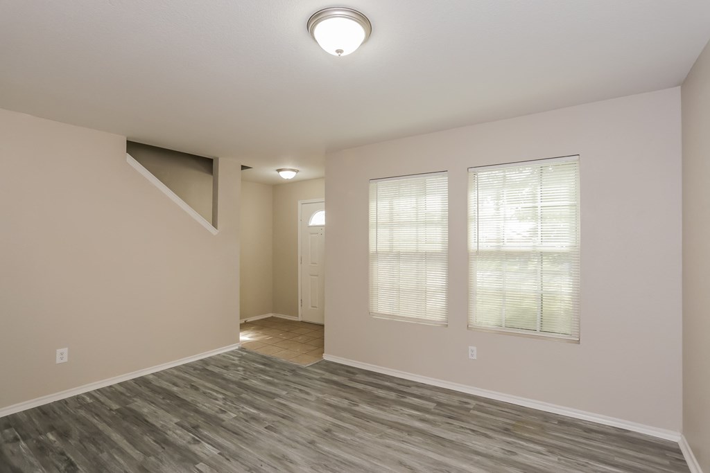 A room with a grey floor and a window with blinds.