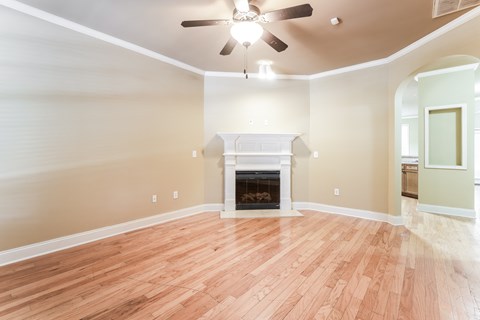 an empty living room with a fireplace and a ceiling fan