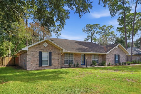 A house with a brown roof and a green lawn in front.