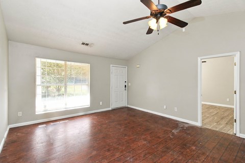 A room with a ceiling fan and wood flooring.