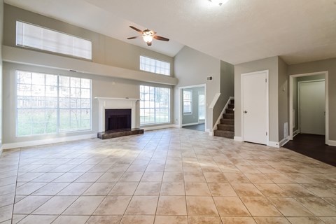 A spacious living room with a fireplace and a staircase.