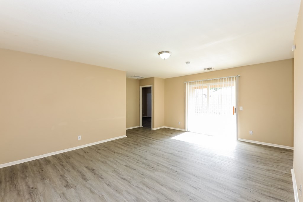 A room with wooden flooring and a door leading to another room.