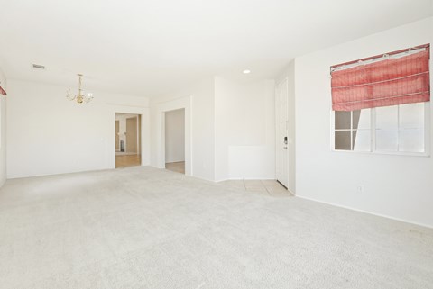 A large, empty room with a carpeted floor and a chandelier hanging from the ceiling.