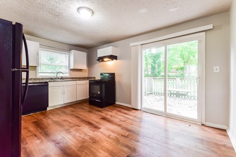 A kitchen with a black fridge and wooden floors.