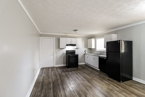 A kitchen with black appliances and wooden floors.