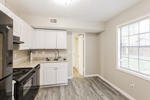 A kitchen with white cabinets and a black stove top oven.