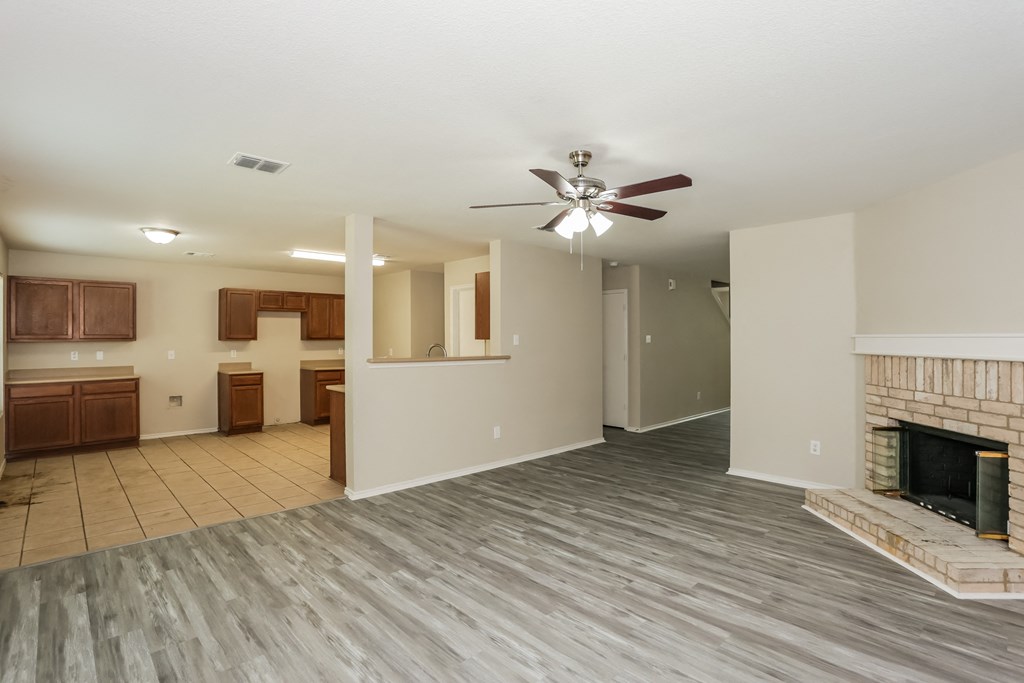 A living room with a fireplace and a ceiling fan.