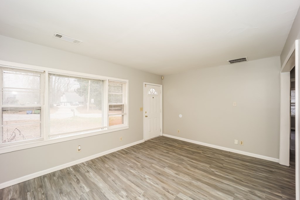 A room with a wooden floor and a door leading to another room.