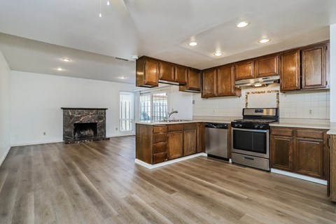 an open kitchen and living room with wooden cabinets and a fireplace