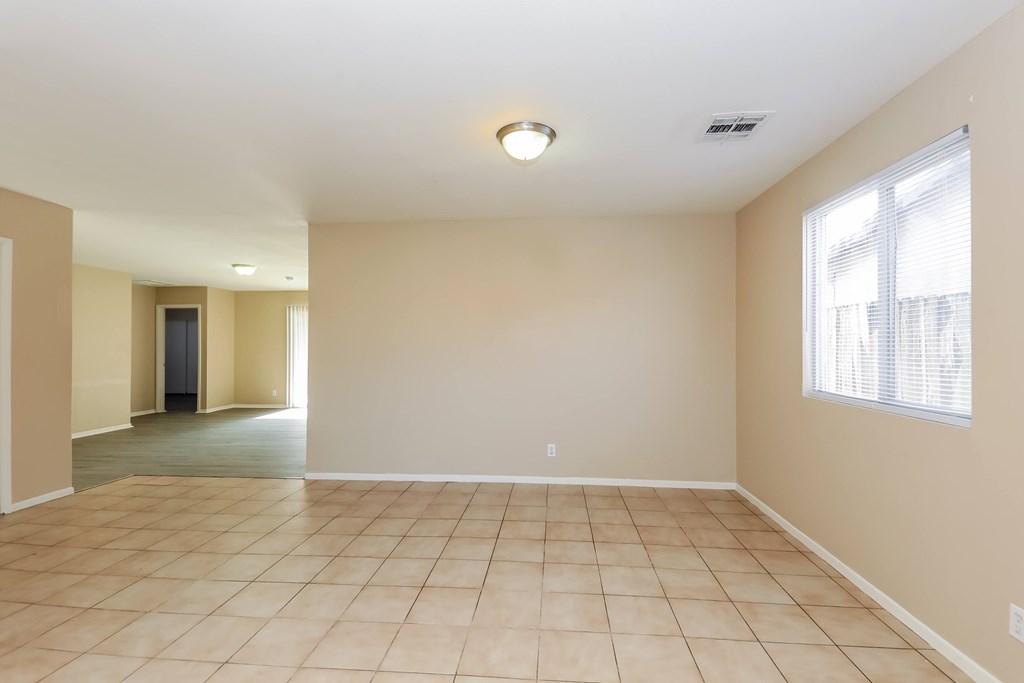 A spacious room with beige walls and tile flooring.