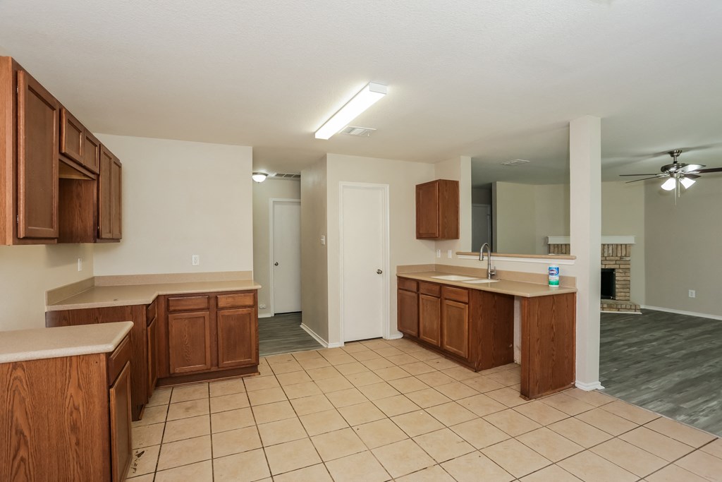 A kitchen with wooden cabinets and a tiled floor.