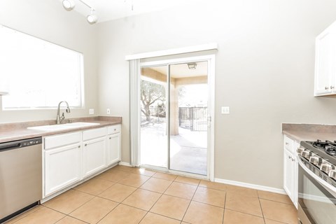 A kitchen with white cabinets and a tiled floor.