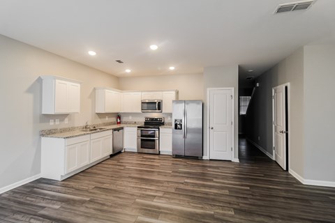 A kitchen with white cabinets and a wooden floor.