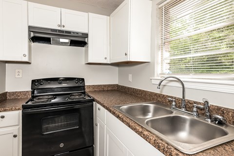 A black stove in a kitchen with white cabinets.