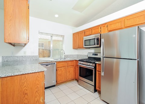 A kitchen with a refrigerator, microwave, oven, and dishwasher.