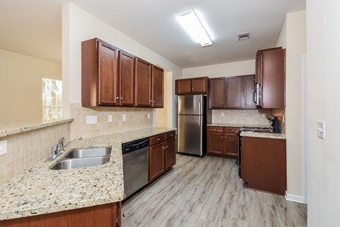 A kitchen with brown cabinets and a granite countertop.