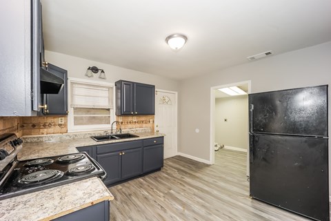 A kitchen with a black refrigerator and a stove top oven.