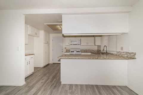 A kitchen with white cabinets and a marble countertop.