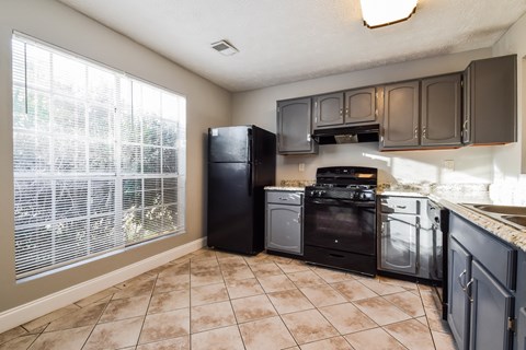 A kitchen with black appliances and brown cabinets.