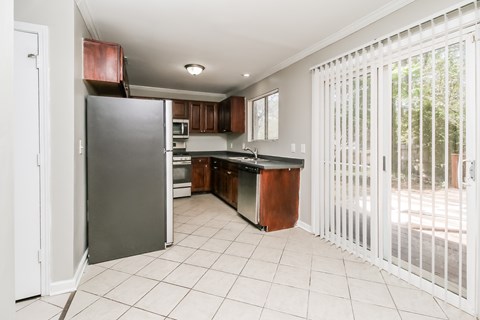 A kitchen with white tile flooring and a white refrigerator.