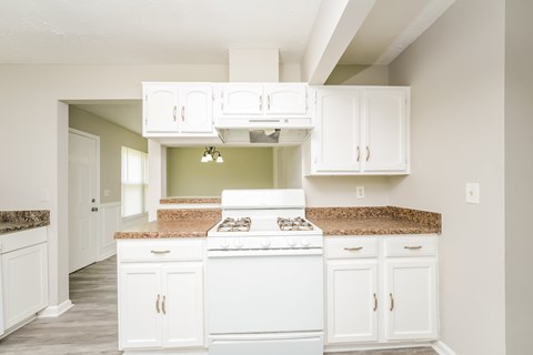 A kitchen with white cabinets and a granite countertop.