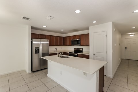 A kitchen with white countertops and a refrigerator.