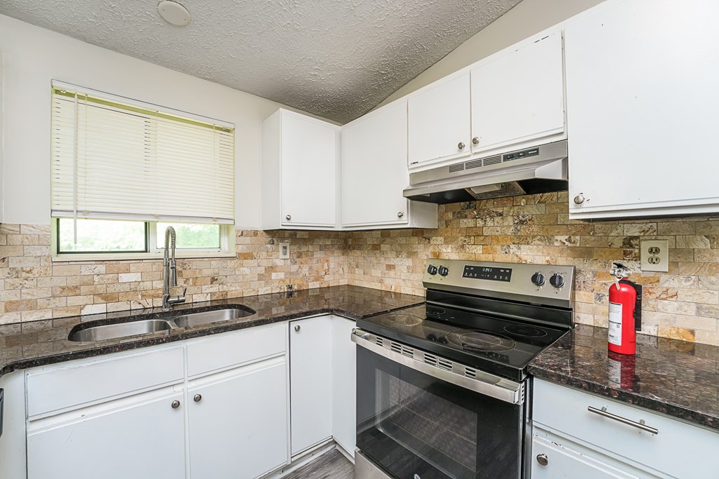 A kitchen with white cabinets and a black stove top oven.
