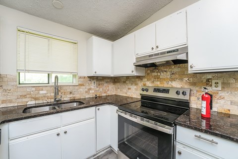 A kitchen with white cabinets and a black stove top oven.