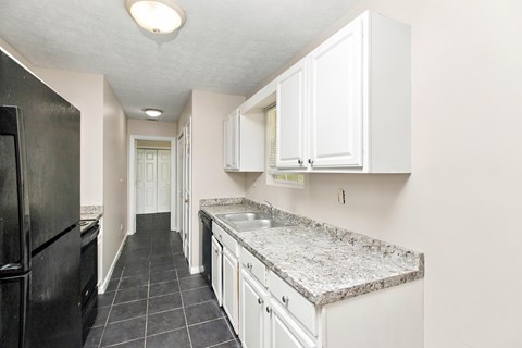 A kitchen with black appliances and white cabinets.