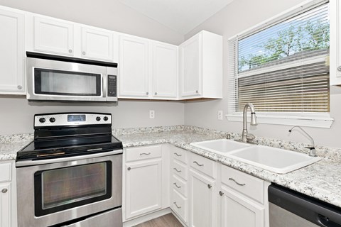 A kitchen with white cabinets and a black stove top oven.