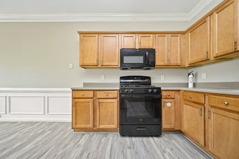 A kitchen with wooden cabinets and a black oven.