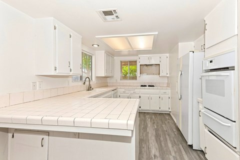 A white kitchen with a refrigerator on the right.