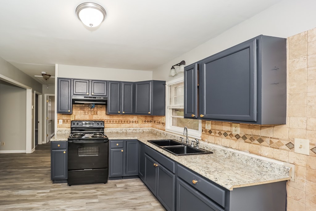 A kitchen with dark blue cabinets and a black stove top oven.