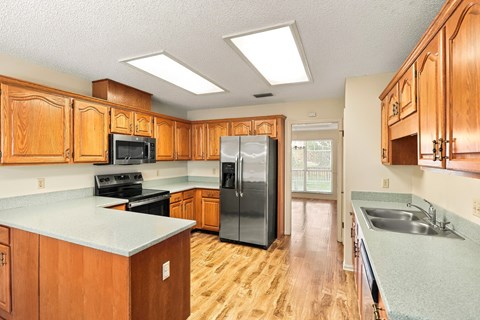 A kitchen with wooden cabinets and a black refrigerator.