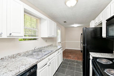 A kitchen with black appliances and white cabinets.