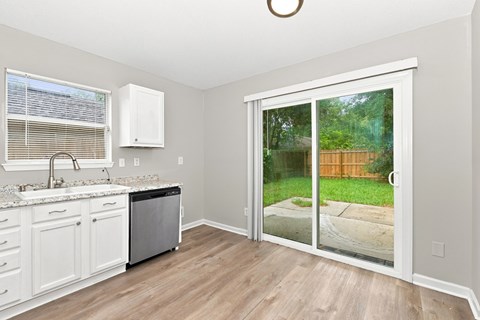 A kitchen with white cabinets and a black dishwasher.
