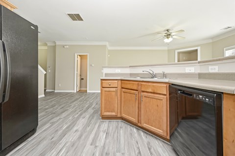A kitchen with a black fridge and wooden cabinets.