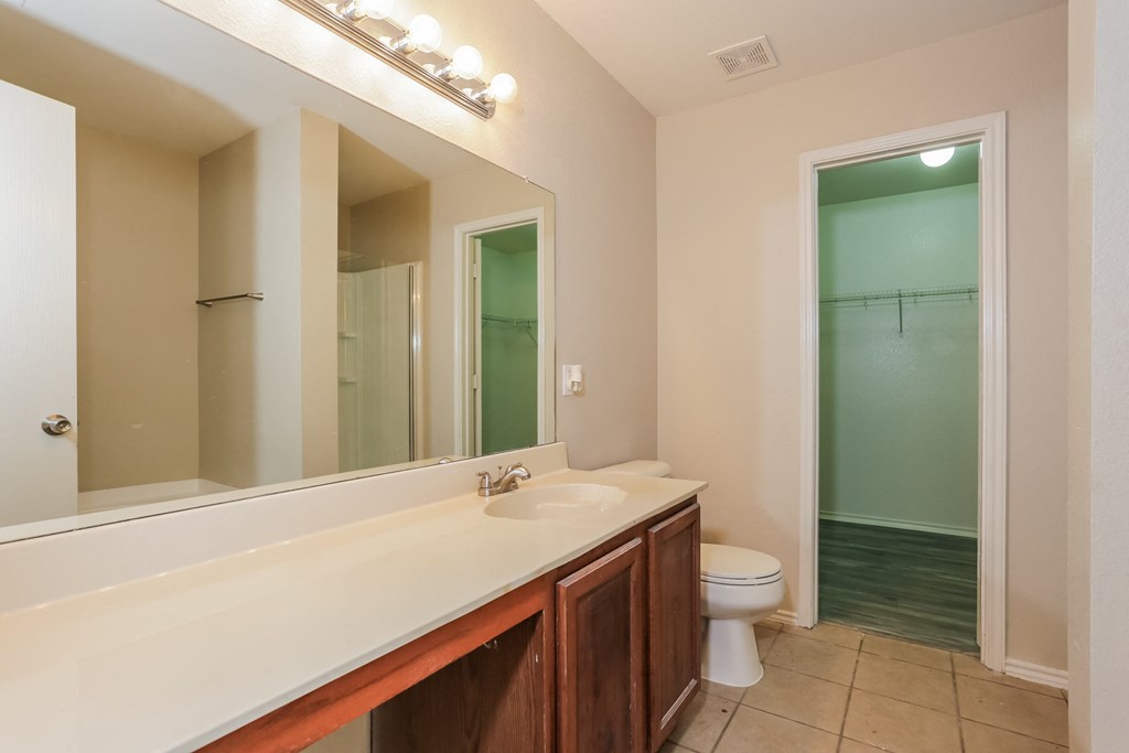 A bathroom with a toilet, sink, and mirror.