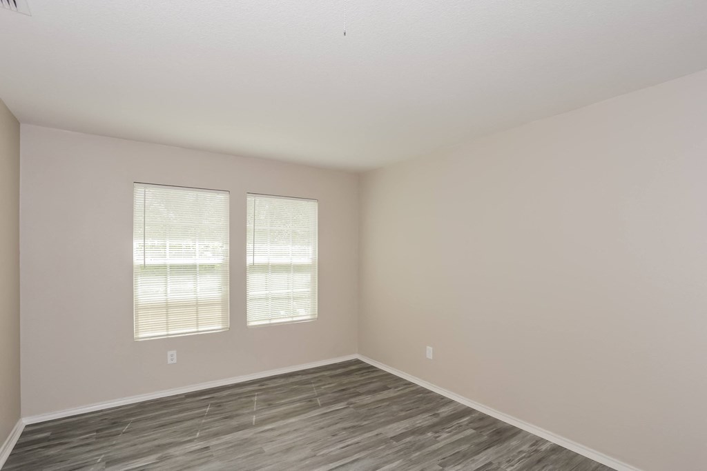 A room with a wooden floor and two windows.