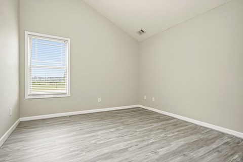 A room with a window and wooden flooring.
