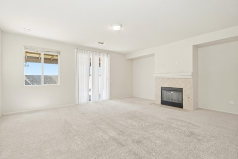 A spacious living room with a fireplace and carpeted floor.