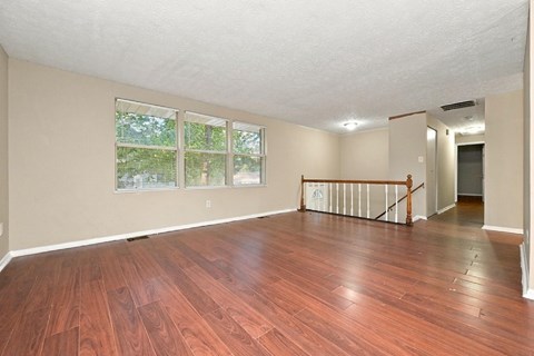 A room with wooden floors and a window overlooking a green area.