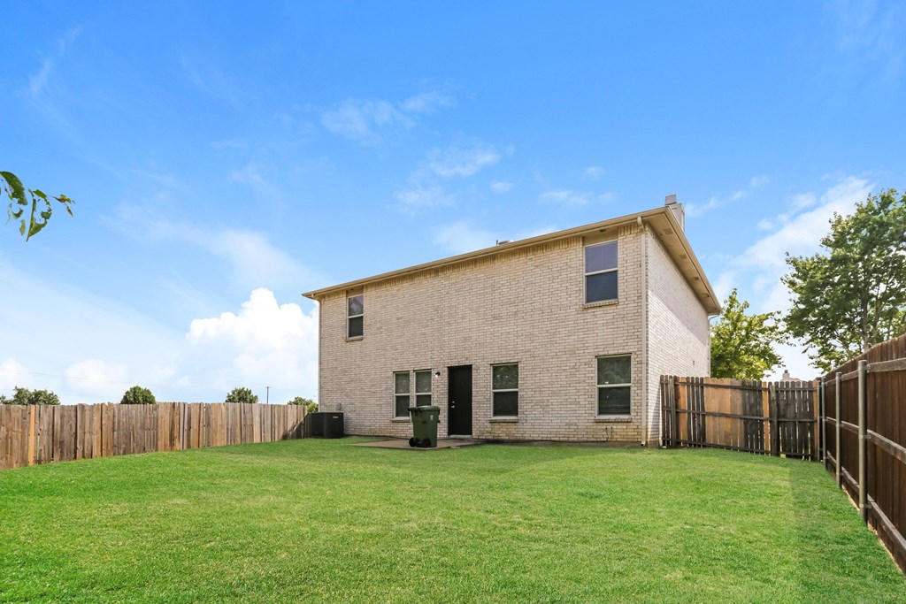 A house with a fence and green grass in front.